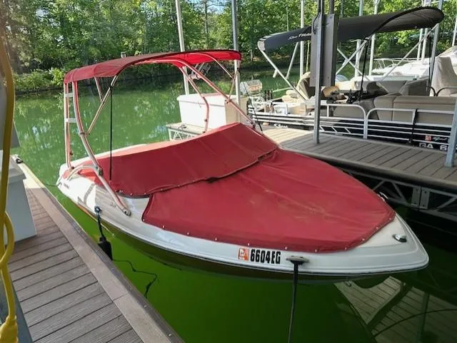 Slide: The Image of 2010 Four Winns H190 boat with red cover docked on a calm lake. - 2