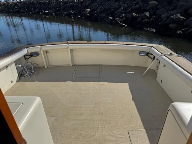 Slide: The Image of 1989 Egg Harbor 35 Sport Fisherman boat deck with calm water and rocky shoreline. - 8