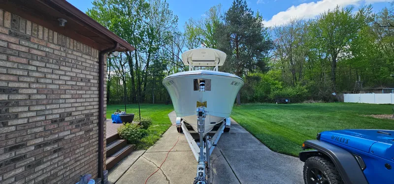 Slide: The Image of 2017 Cobia 277 Center Console boat on trailer in driveway, surrounded by greenery. - 10