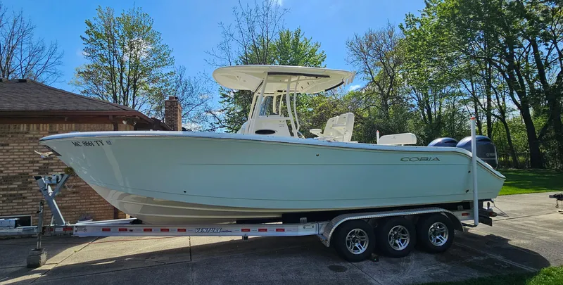 Slide: The Image of 2017 Cobia 277 Center Console boat on a trailer, parked outdoors. - 2