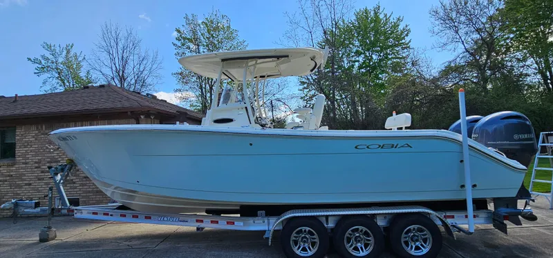 Slide: The Image of 2017 Cobia 277 Center Console boat on a trailer, parked outdoors. - 3