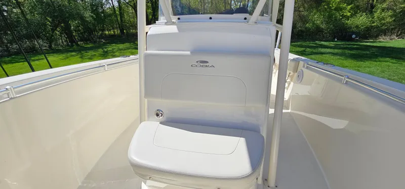 Slide: The Image of 2017 Cobia 277 Center Console boat with white seating and console, surrounded by greenery. - 43
