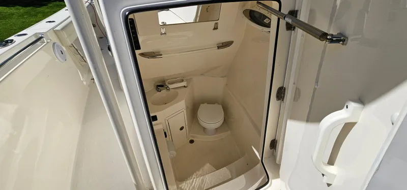 Slide: The Image of 2017 Cobia 277 Center Console boat interior with compact marine toilet and sink. - 46