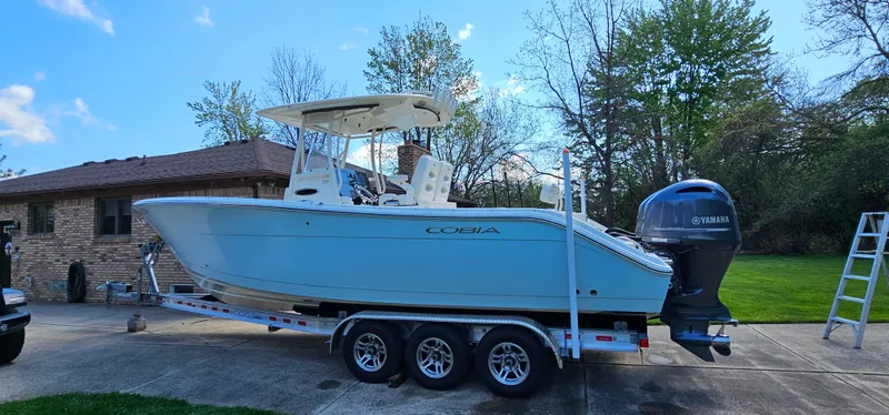 Slide: The Image of 2017 Cobia 277 Center Console boat on trailer, parked in driveway near house. - 5