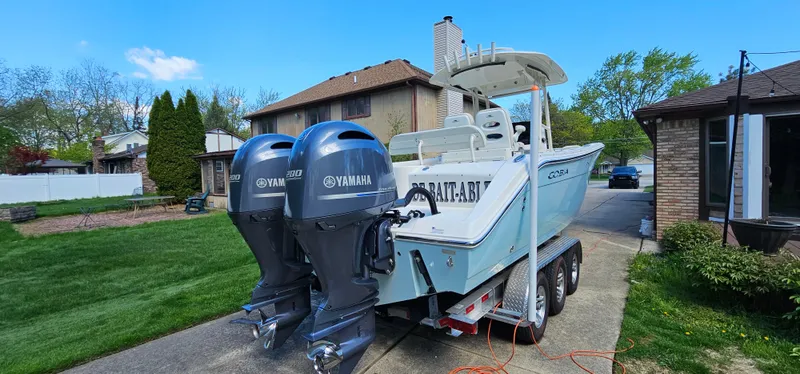 Slide: The Image of 2017 Cobia 277 Center Console boat with dual Yamaha engines on a trailer in a suburban driveway. - 8