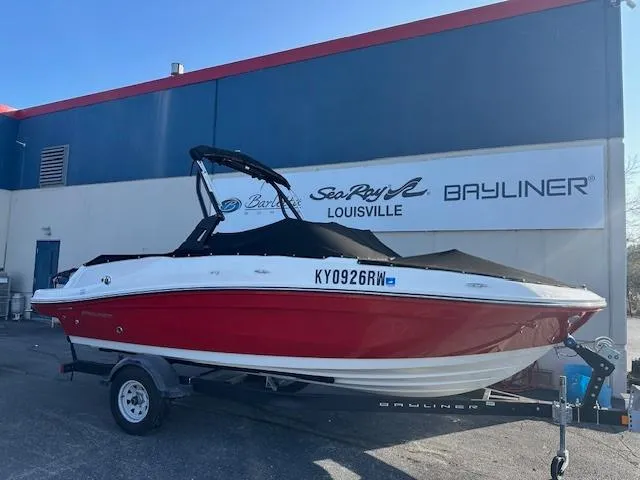 The Image of 2021 Bayliner VR5 Bowrider I/O boat in red, parked on a trailer outside dealership. - 1