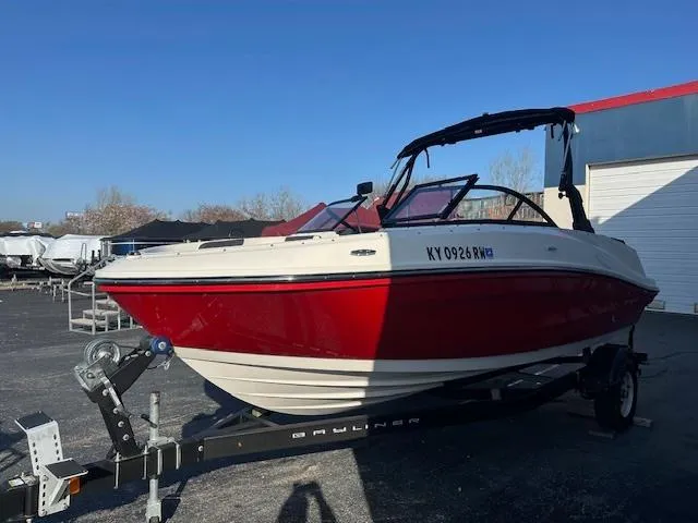 Slide: The Image of 2021 Bayliner VR5 Bowrider I/O boat on trailer, red and white exterior, parked outdoors. - 4