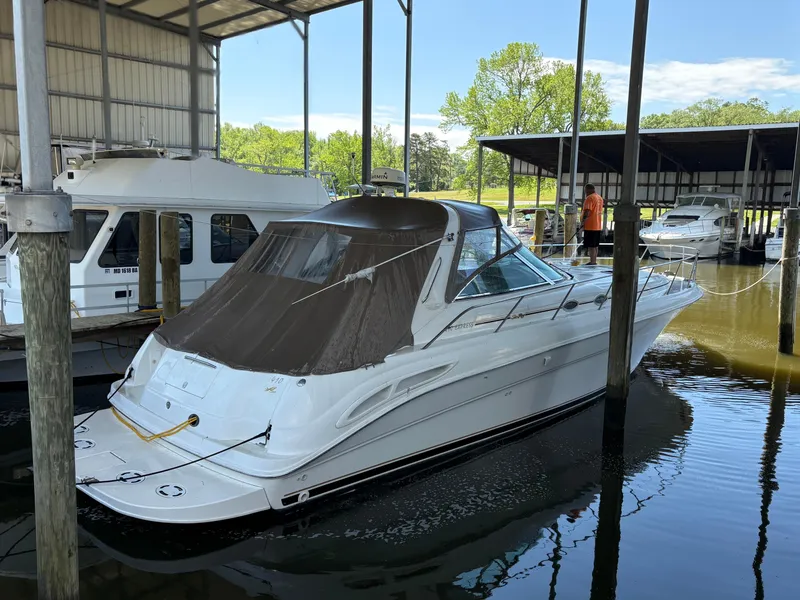 The Image of 1999 Sea Ray 410 Express Cruiser docked in a marina under a covered shelter. - 0
