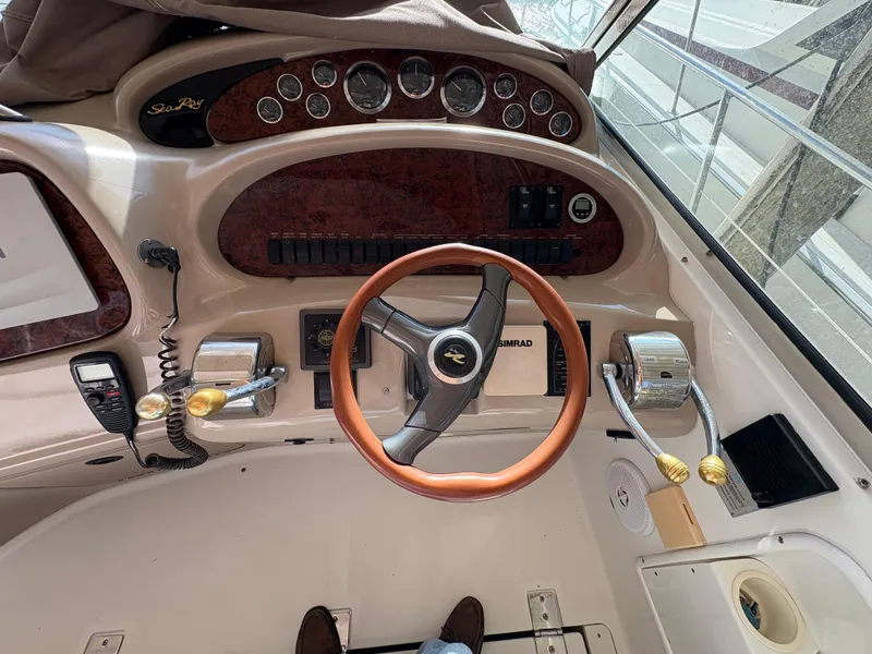 Slide: The Image of 1999 Sea Ray 410 Express Cruiser helm with wood-accented steering wheel and control panel. - 15