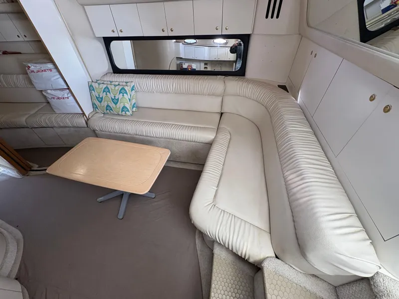 Slide: The Image of Interior of 1999 Sea Ray 410 Express Cruiser with white leather seating and wooden table. - 4