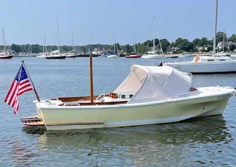 The Image of A 2023 Dyer Glamour Girl boat on water, with a person steering and an American flag. - 0