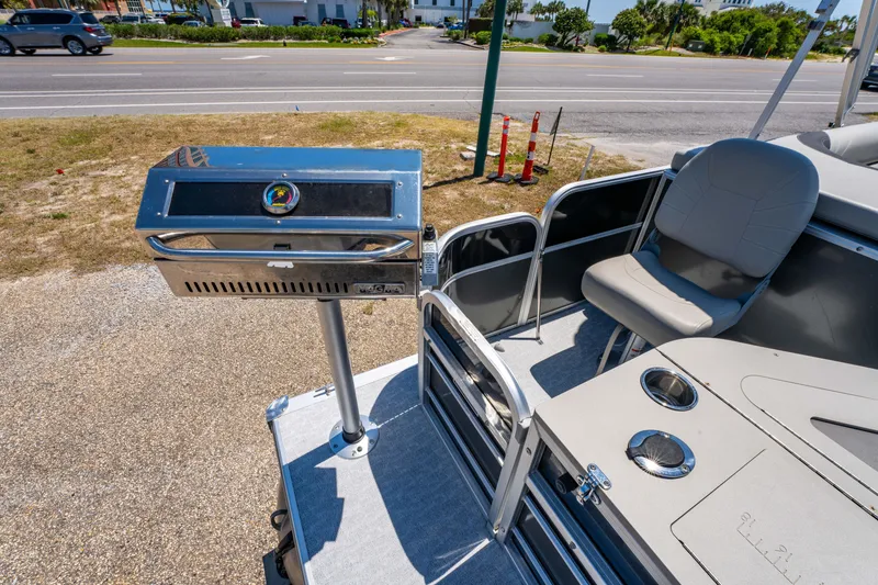 Slide: The Image of 2021 South Bay 224FCR boat with grill and seating area, parked near a road. - 17