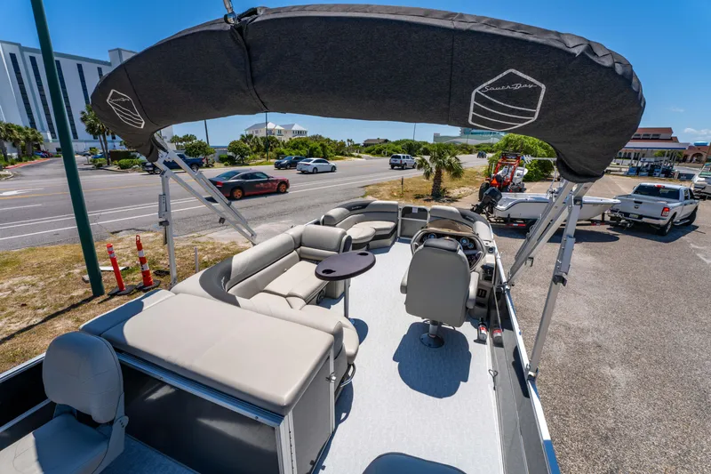 Slide: The Image of 2021 South Bay 224FCR pontoon boat with canopy, parked near a road under clear blue skies. - 19