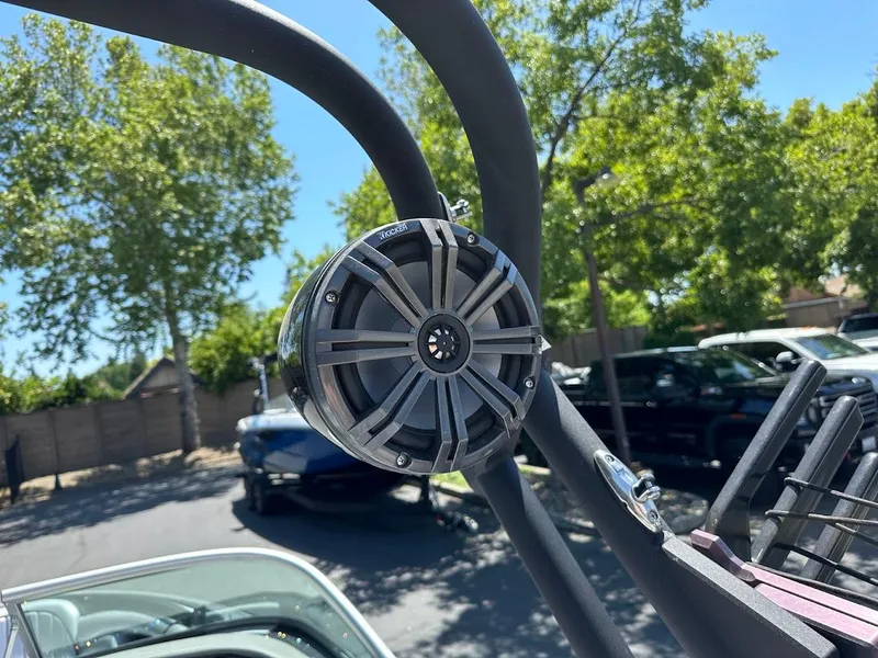 Slide: The Image of Speaker mounted on a 2025 Sanger V215 SX boat, with trees and cars in the background. - 24