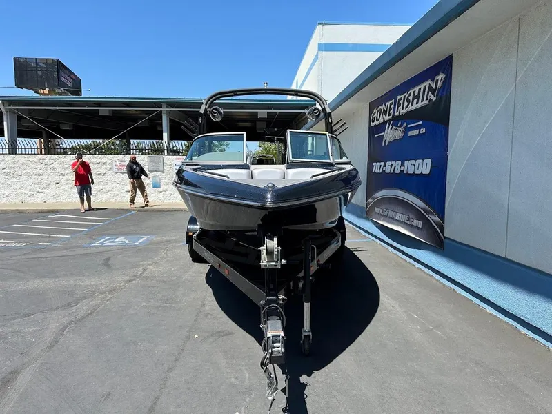 Slide: The Image of 2025 Sanger V215 SX boat on trailer in parking lot, near "Gone Fishin'" sign. - 3