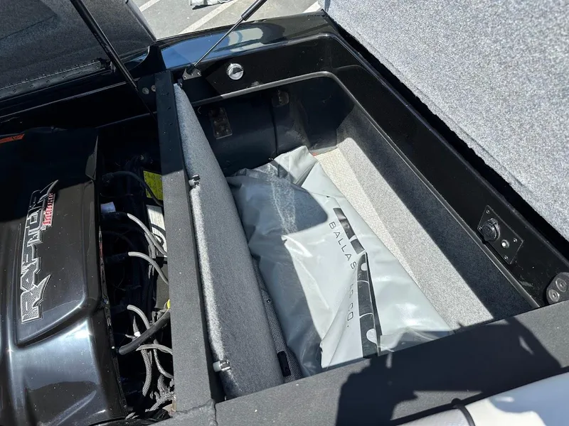 Slide: The Image of Open storage compartment in a 2025 Sanger V215 SX boat, showing engine and ballast bag. - 30