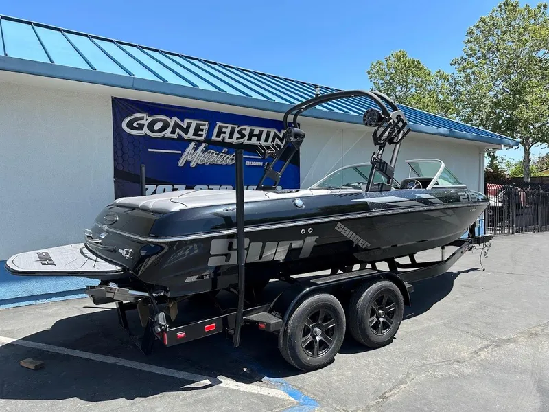 Slide: The Image of 2025 Sanger V215 SX boat on trailer, parked outside a building with "Gone Fishing" sign. - 5