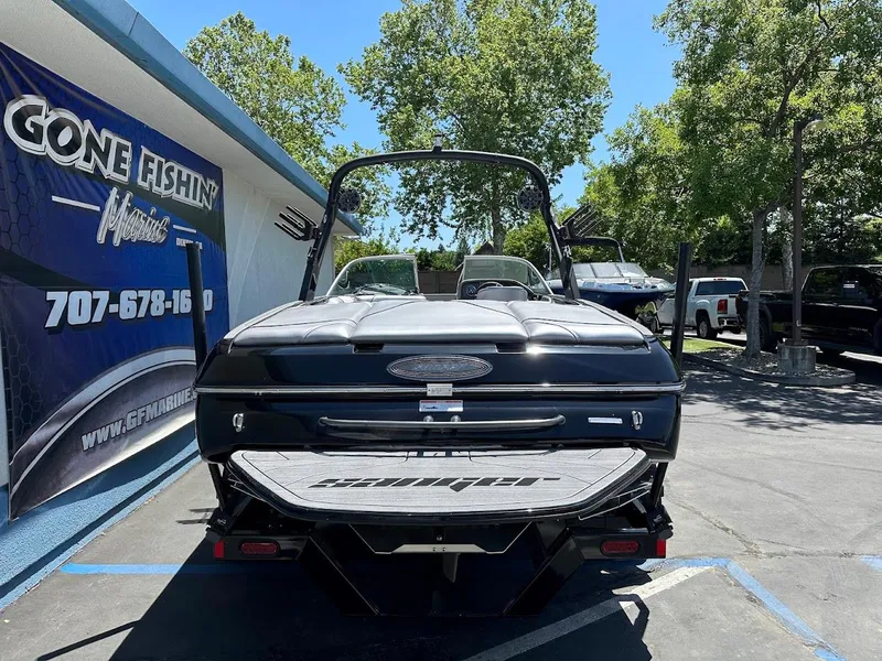 Slide: The Image of 2025 Sanger V215 SX boat parked outdoors near a fishing store. - 6