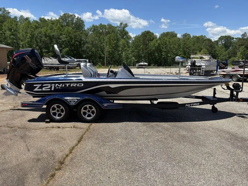 Slide: The Image of 2025 Nitro Z21 XL boat on trailer, parked outdoors, with trees in the background. - 6