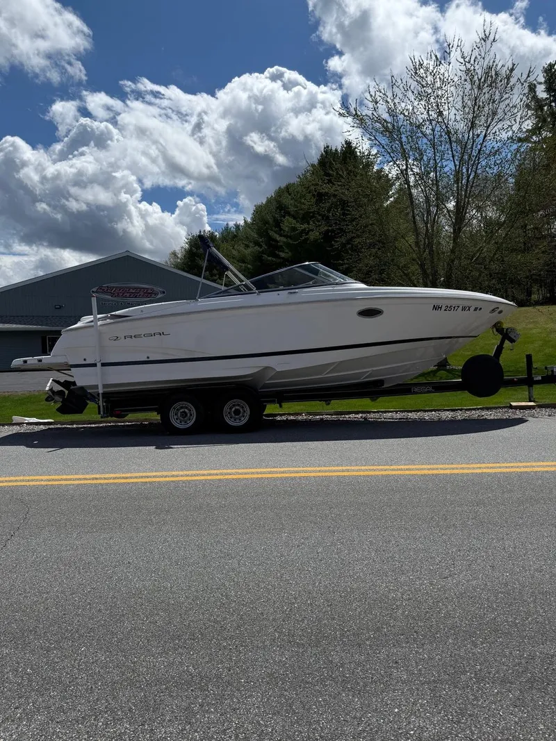 Slide: The Image of 2008 Regal 2750 boat on trailer, parked roadside under cloudy sky. - 1