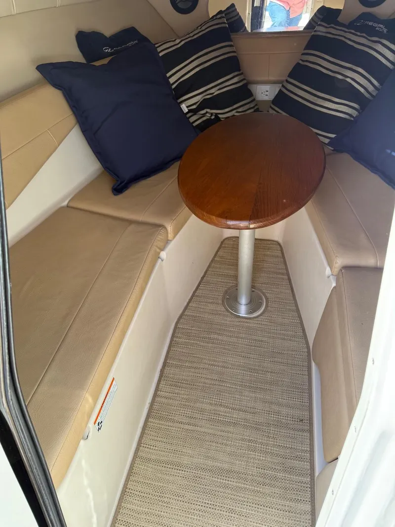 Slide: The Image of Interior of 2008 Regal 2750 boat with cushioned seating and wooden table. - 17
