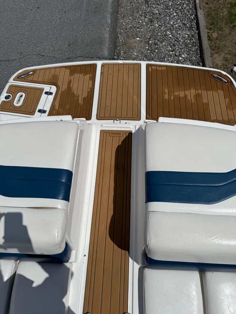 Slide: The Image of 2008 Regal 2750 boat deck with white and blue seating, wooden flooring. - 24
