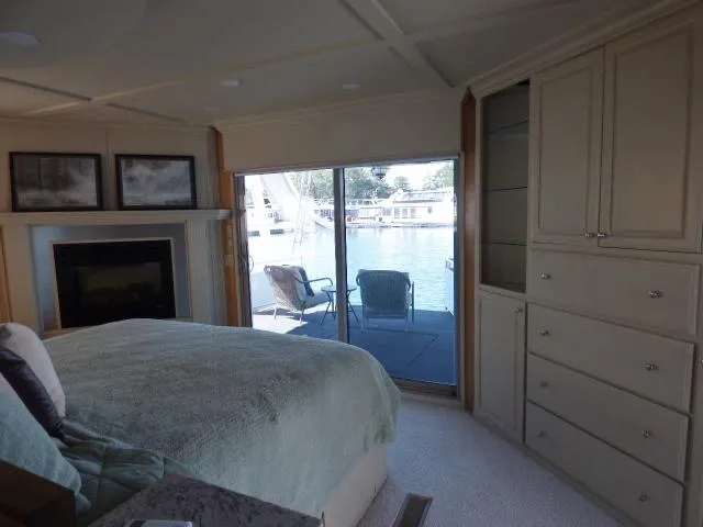 Slide: The Image of Luxurious Sumerset 20x103 houseboat bedroom with waterfront view, fireplace, and elegant furnishings. - 12