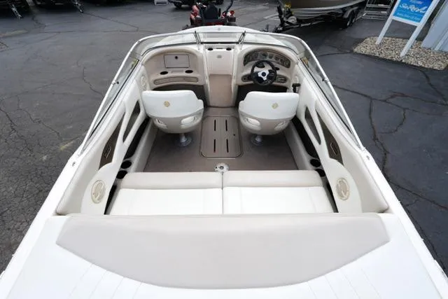 Slide: The Image of 2004 Bryant 200 boat interior with white seating and steering wheel, parked on asphalt. - 7
