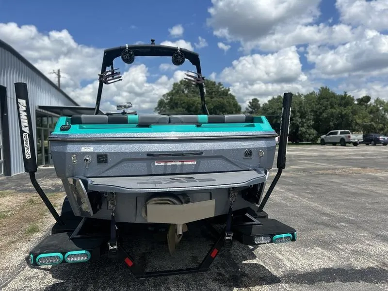 Slide: The Image of 2023 Axis A225 boat rear view, parked outdoors under a partly cloudy sky. - 1