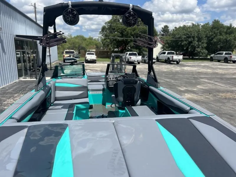 Slide: The Image of 2023 Axis A225 boat with teal and gray interior, parked outdoors under a blue sky. - 2