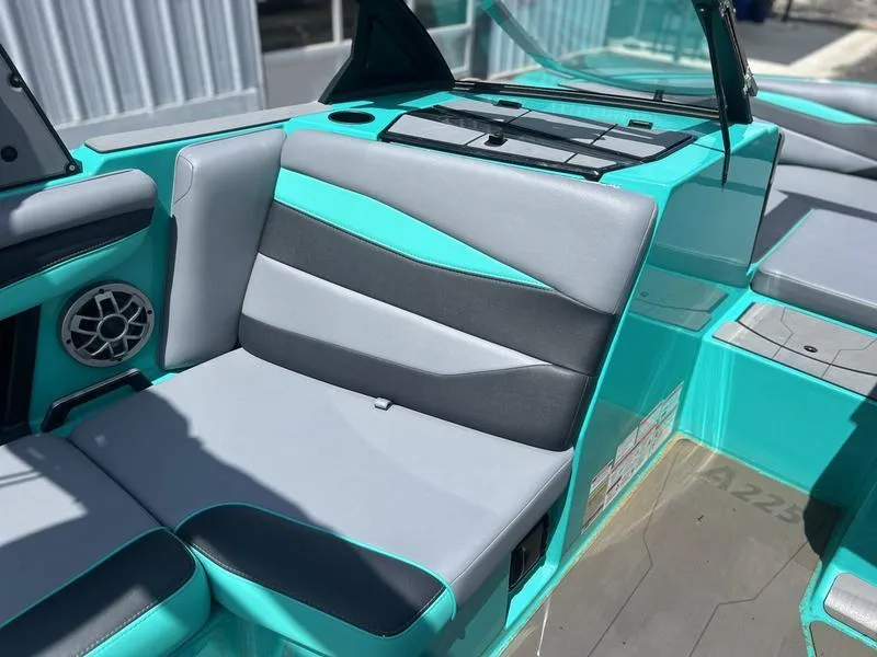 Slide: The Image of 2023 Axis A225 boat interior with teal and gray seating, cup holder, and speaker. - 5