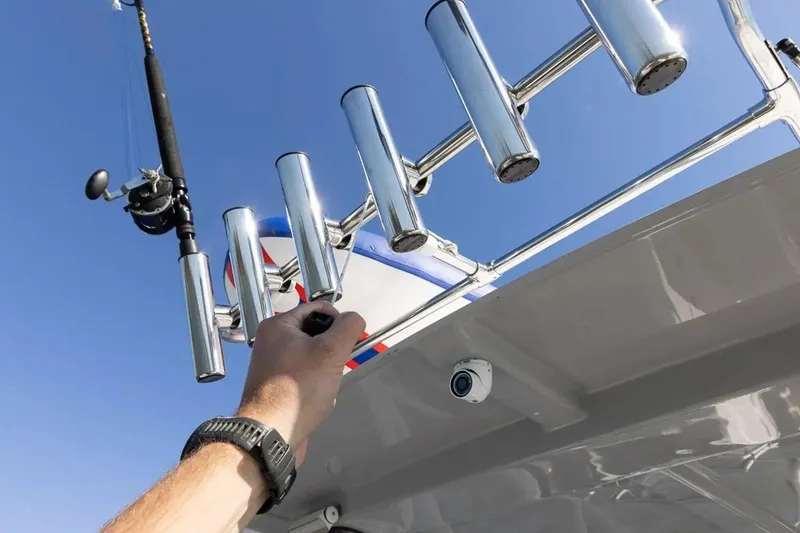 Slide: The Image of Hand adjusting fishing rod holder on Solara S-250 DC boat, 2025 model, under clear blue sky. - 17