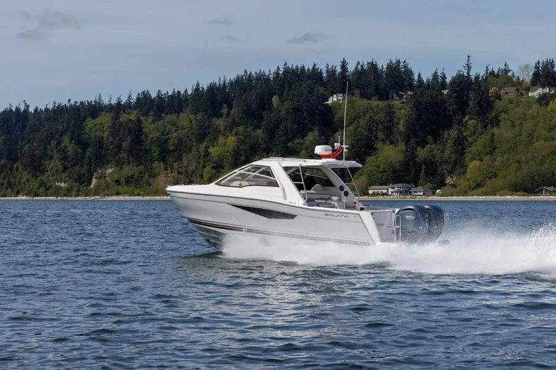 The Image of 2025 Solara S-310 SC boat cruising on a scenic lake with forested shoreline. - 0