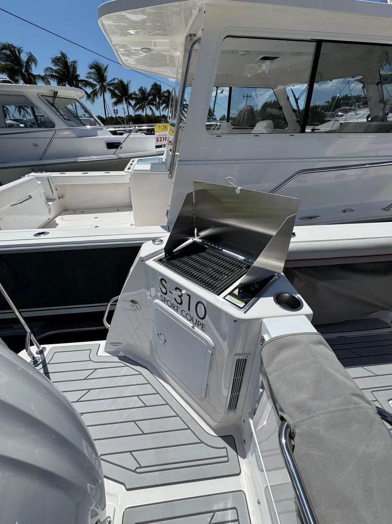 Slide: The Image of 2025 Solara S-310 SC boat with outdoor grill, docked under sunny skies. - 6