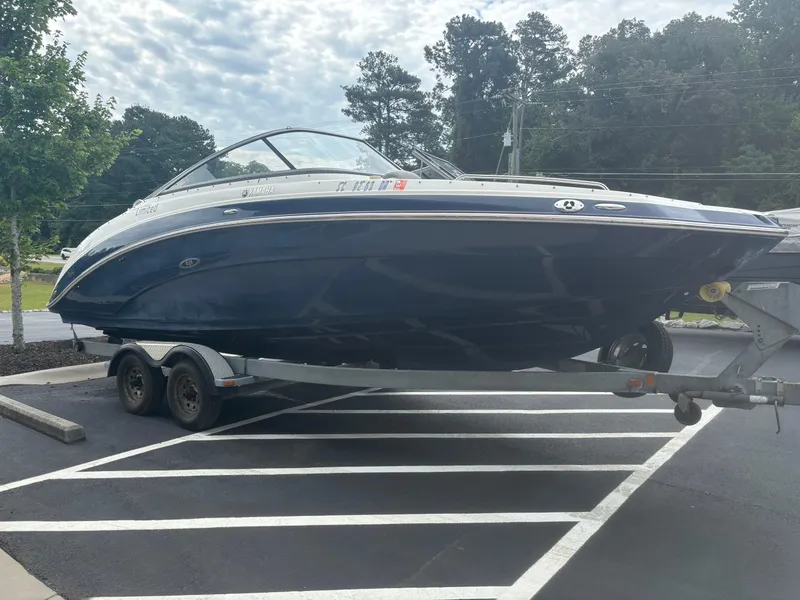 Slide: The Image of 2012 Yamaha Boats 242 Limited on trailer in parking lot, surrounded by trees. - 4