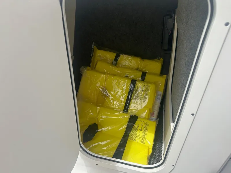 Slide: The Image of Yellow life jackets stored in a compartment of a 2023 Chaparral 23 SSi boat. - 10