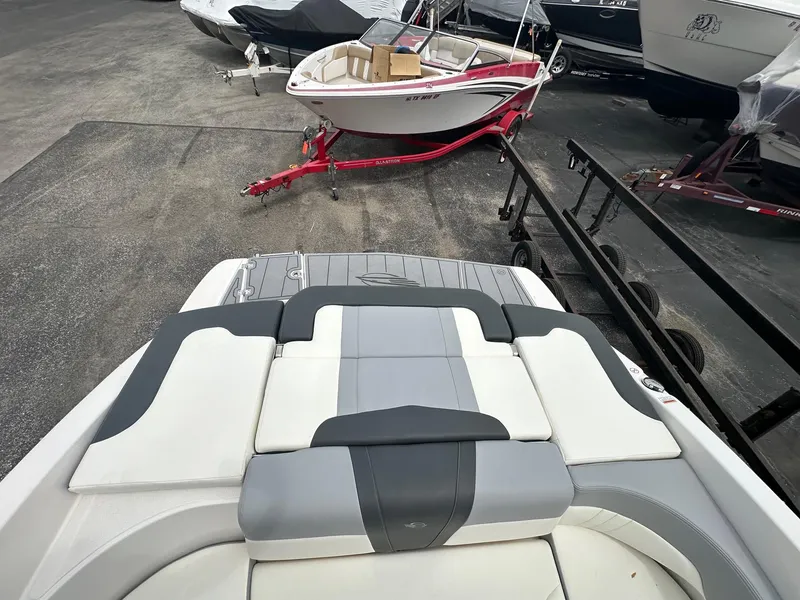 Slide: The Image of 2023 Chaparral 23 SSi boat interior with cushioned seating, parked on a trailer. - 8
