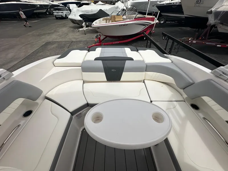 Slide: The Image of 2023 Chaparral 23 SSi boat interior with seating and table, displayed in a showroom. - 9