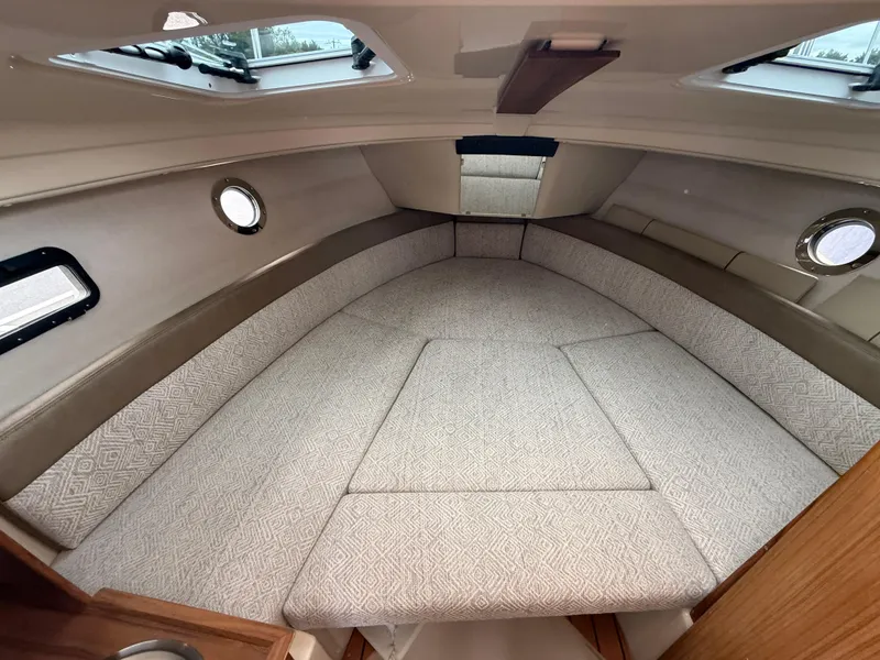 Slide: The Image of 2025 Ranger Tugs R-23 cabin interior with cushioned seating and porthole windows. - 15