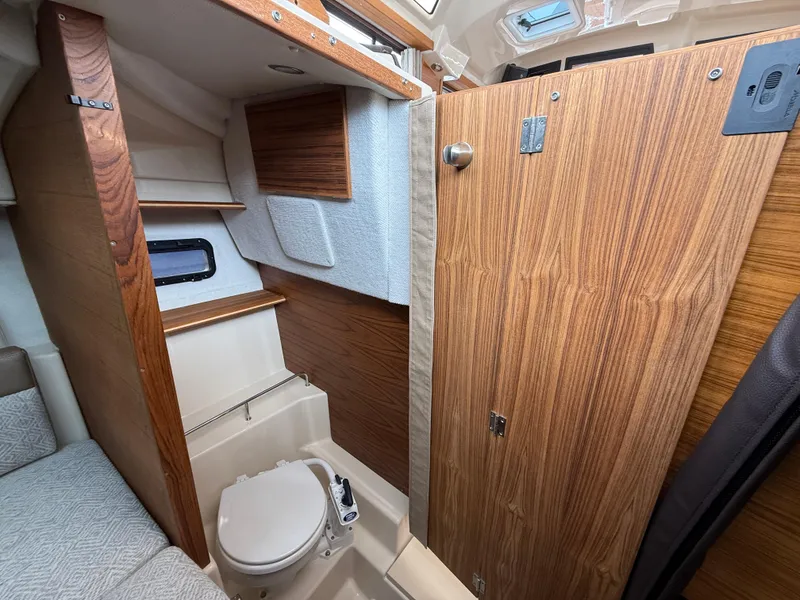 Slide: The Image of 2025 Ranger Tugs R-23 interior bathroom with wood paneling and compact design. - 16