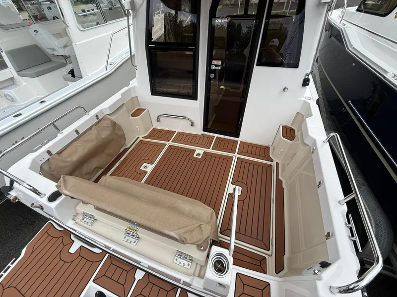 Slide: The Image of 2025 Ranger Tugs R-23 boat deck with teak flooring and cushioned seating. - 5