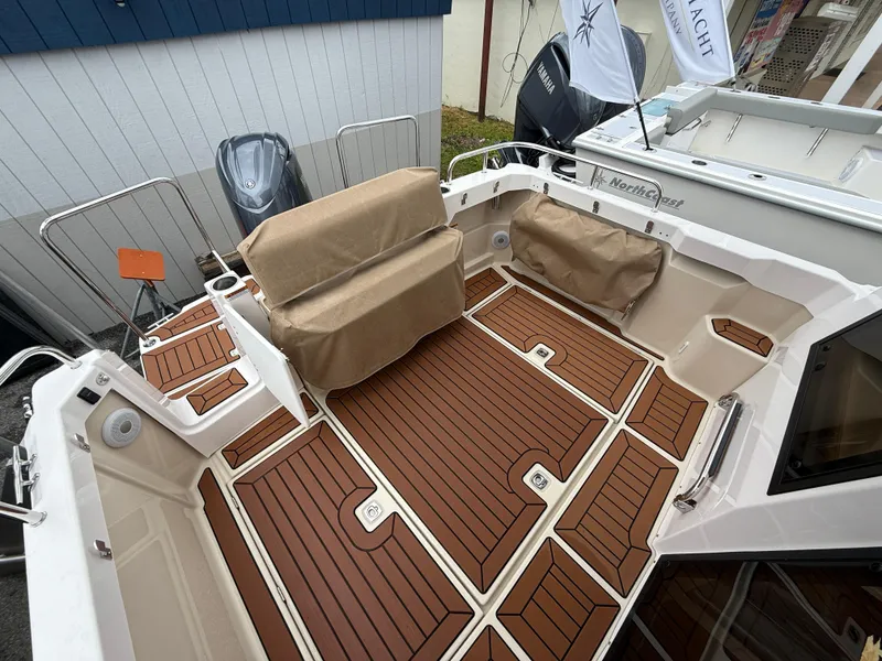 Slide: The Image of 2025 Ranger Tugs R-23 boat deck with cushioned seating and wood-style flooring. - 6