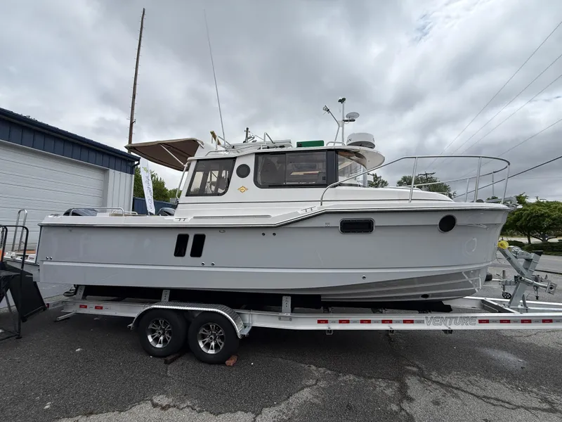 Slide: The Image of 2025 Ranger Tugs R-25 boat on trailer, parked outdoors under cloudy sky. - 0