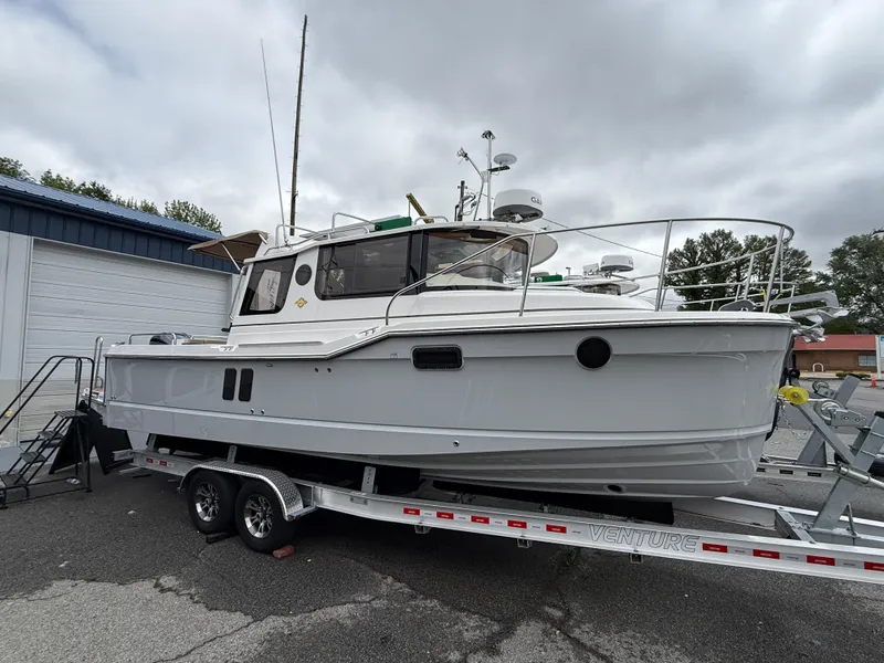 Slide: The Image of 2025 Ranger Tugs R-25 boat on trailer, parked outdoors, overcast sky. - 1