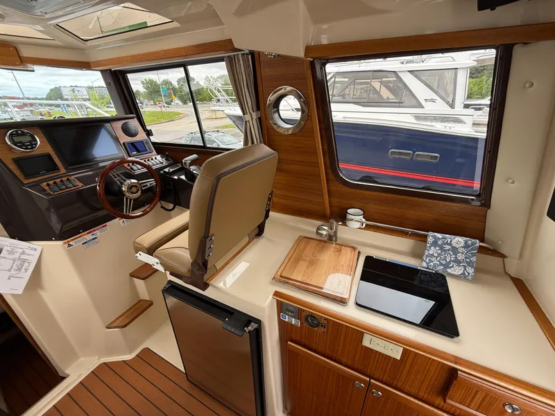 Slide: The Image of Interior of 2025 Ranger Tugs R-25 boat, featuring helm, seating, and kitchenette area. - 11