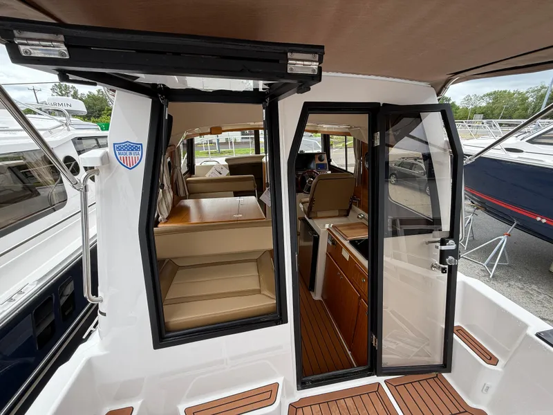 Slide: The Image of 2025 Ranger Tugs R-25 boat interior with seating and helm, featuring modern design and wood accents. - 15