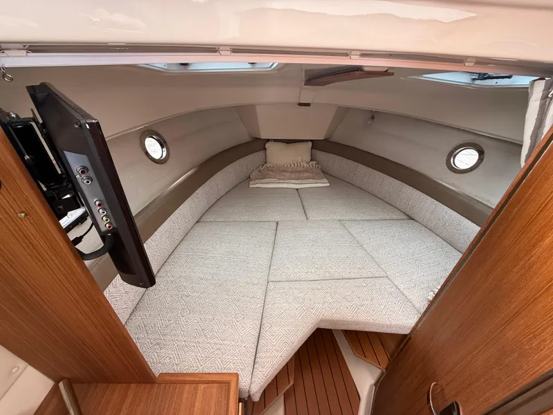 Slide: The Image of 2025 Ranger Tugs R-25 cabin interior with cozy bed and mounted TV. - 18