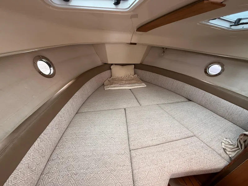 Slide: The Image of 2025 Ranger Tugs R-25 cabin interior with cozy bed and portholes. - 19