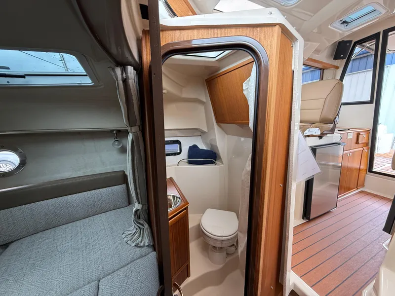 Slide: The Image of 2025 Ranger Tugs R-25 interior with bathroom, seating area, and kitchenette. - 21
