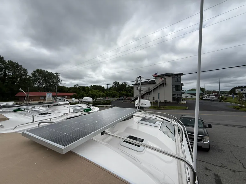 Slide: The Image of 2025 Ranger Tugs R-25 boat with solar panel, parked in a marina under cloudy skies. - 23